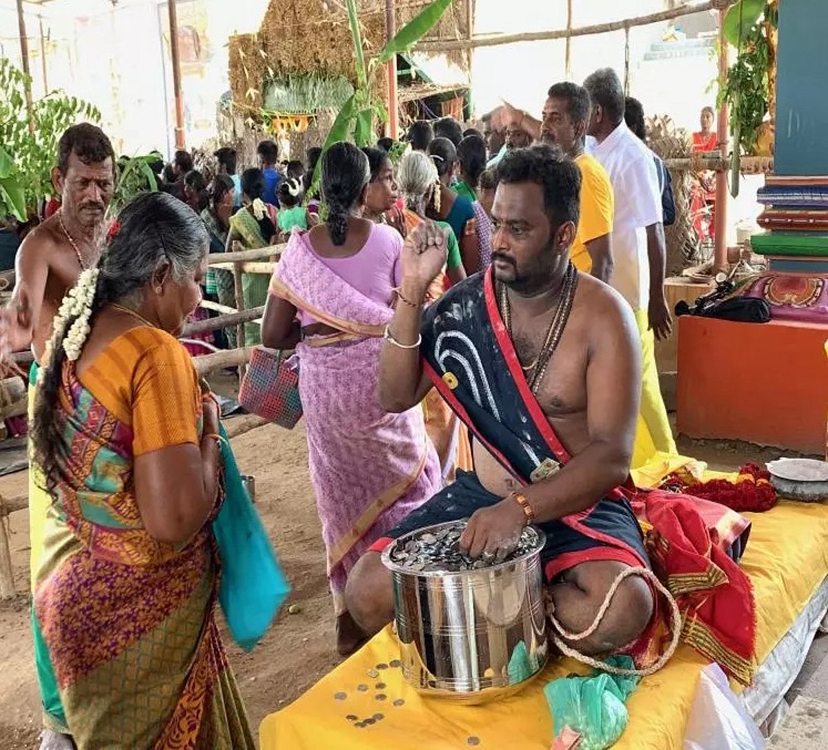 திருச்சியில் கருப்பசாமி கோவில் பூசாரி பக்தர்களுக்குப் பணம் வழங்கிய நிகழ்வு